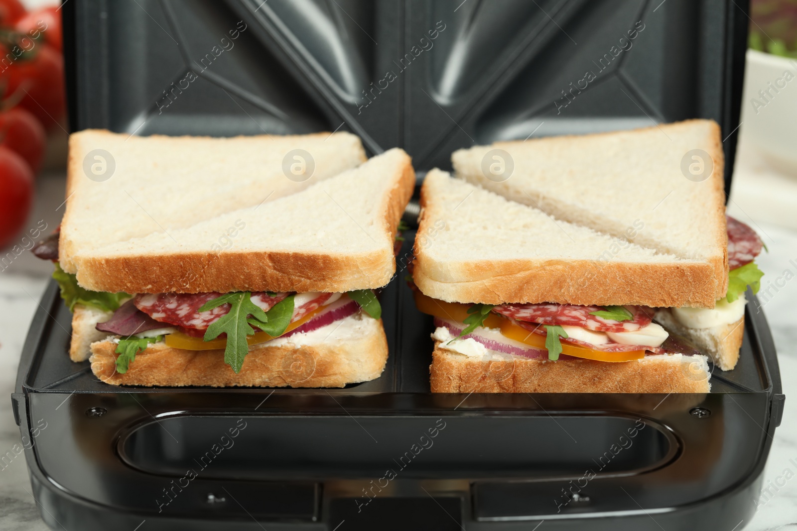 Photo of Modern grill maker with sandwiches on table, closeup view