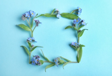 Photo of Frame made of amazing forget-me-not flowers on color background, flat lay. Space for text