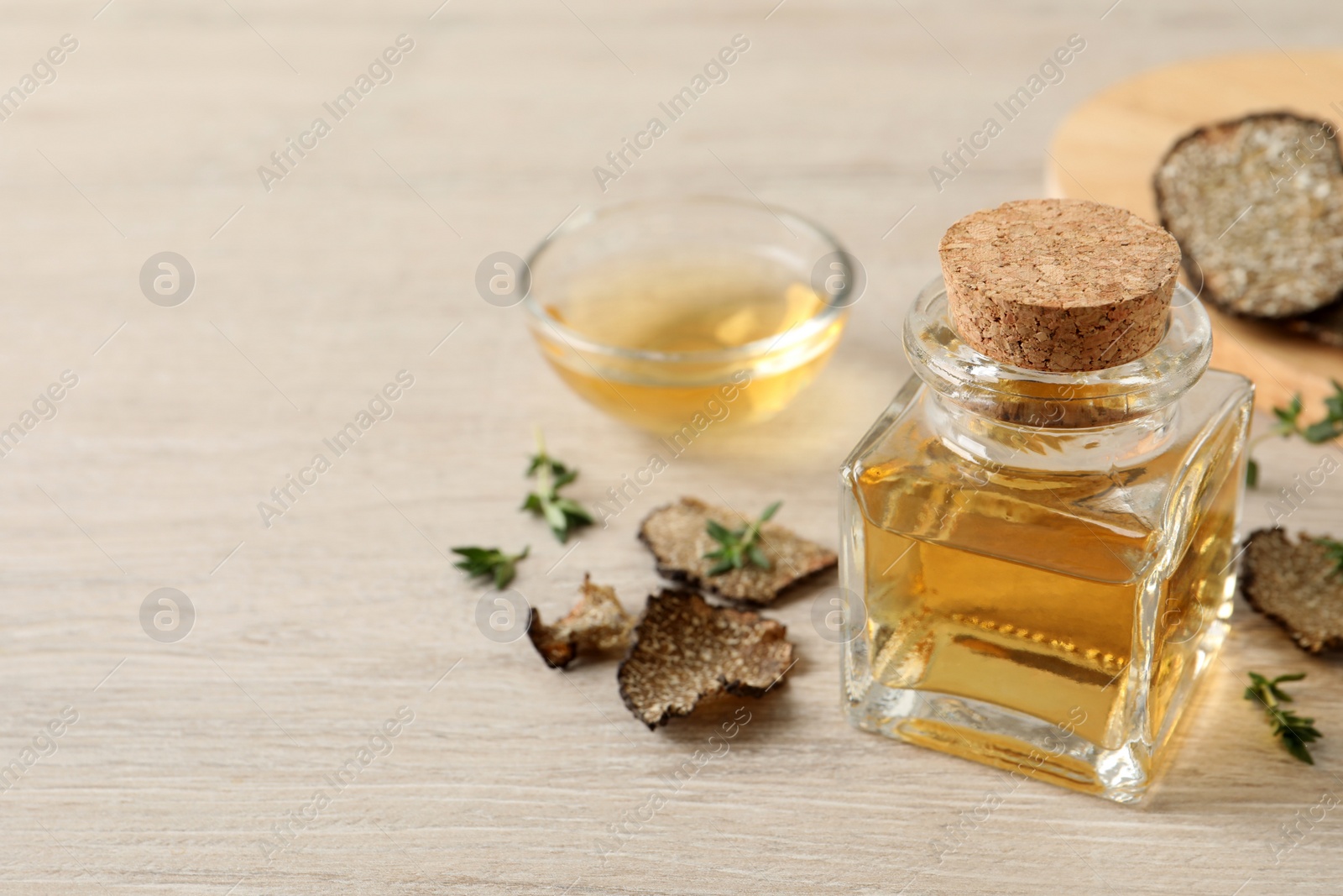 Photo of Fresh truffle oil and thyme on wooden table, space for text