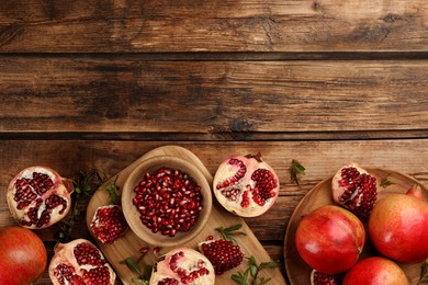 Delicious ripe pomegranates on wooden table, flat lay. Space for text