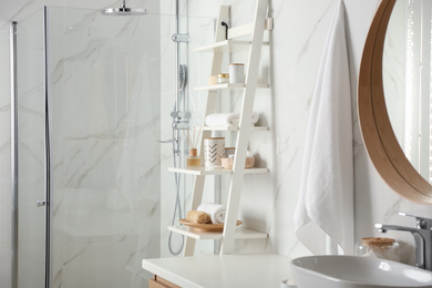 Photo of Shelving unit with different items in bathroom interior