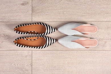 Different female shoes on wooden background, top view