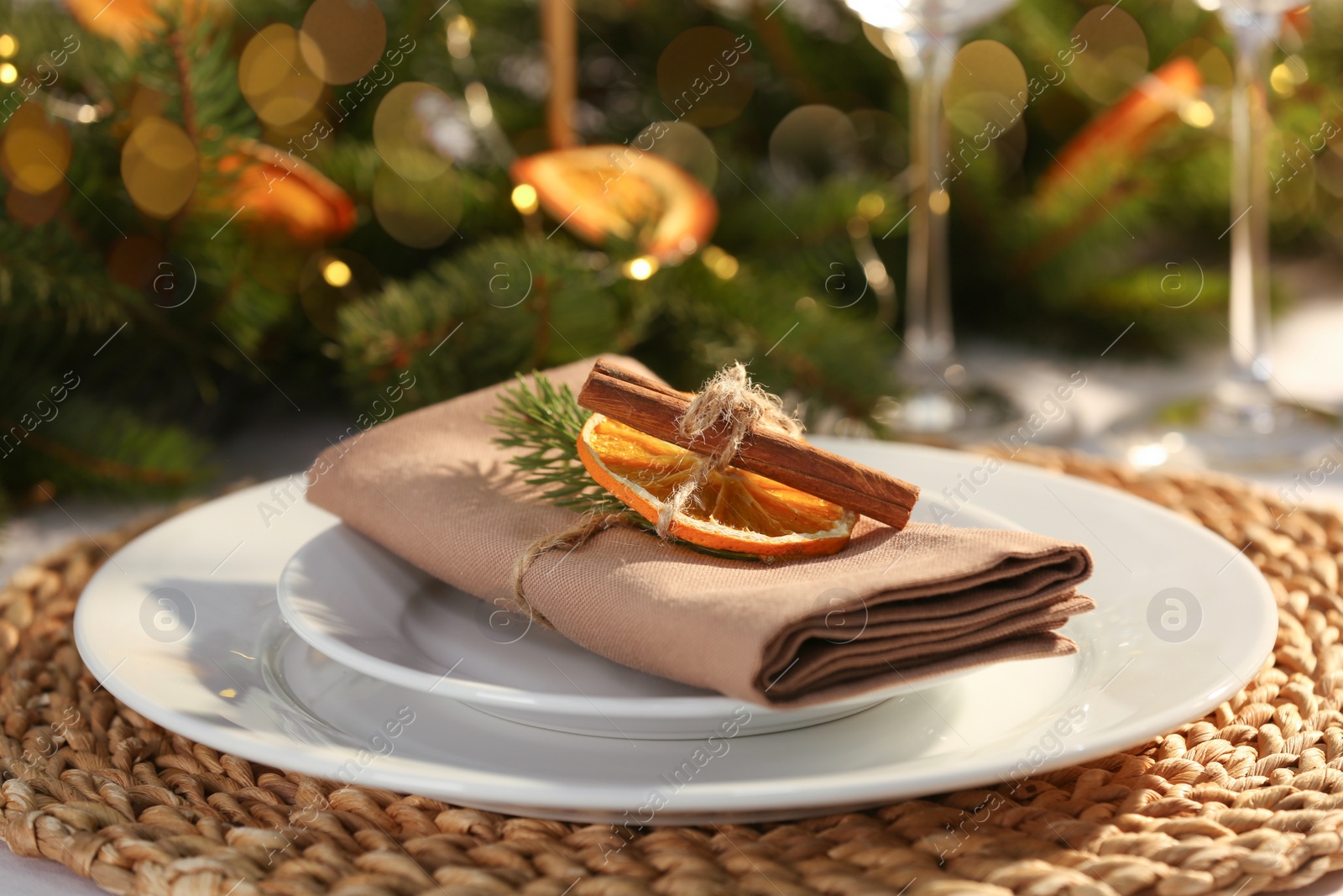 Photo of Festive place setting with beautiful dishware, fabric napkin and dried orange slice for Christmas dinner on white table, closeup