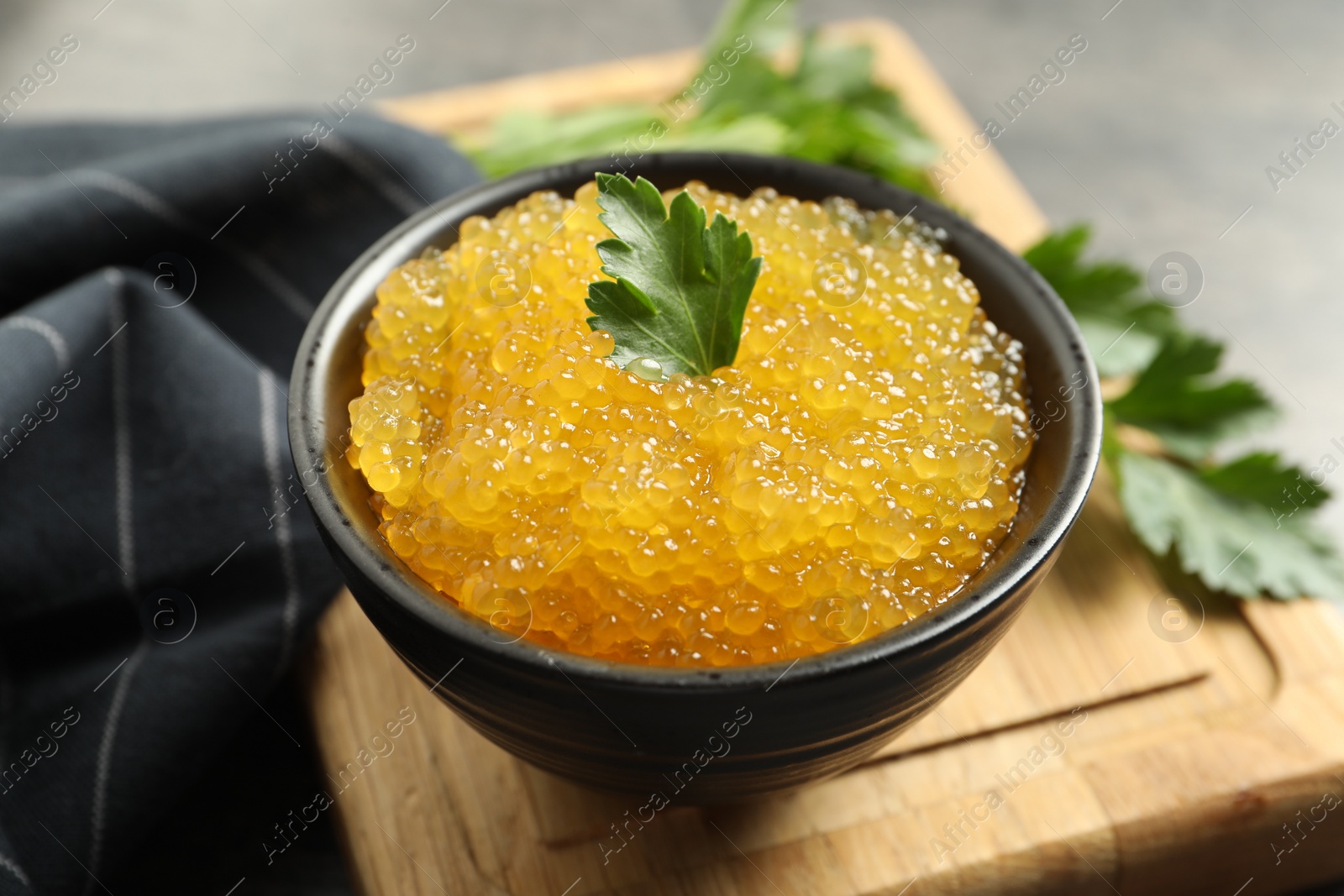 Photo of Fresh pike caviar in bowl and parsley on table, closeup