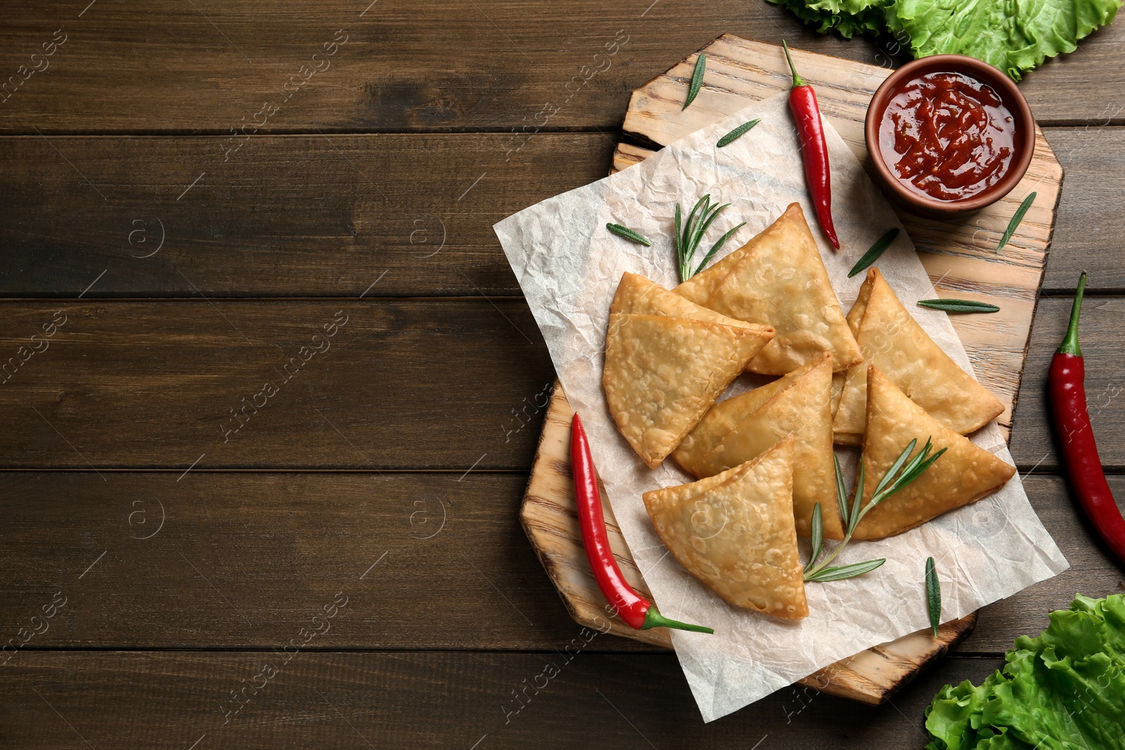 Photo of Fresh delicious crispy samosas served on wooden table, flat lay. Space for text