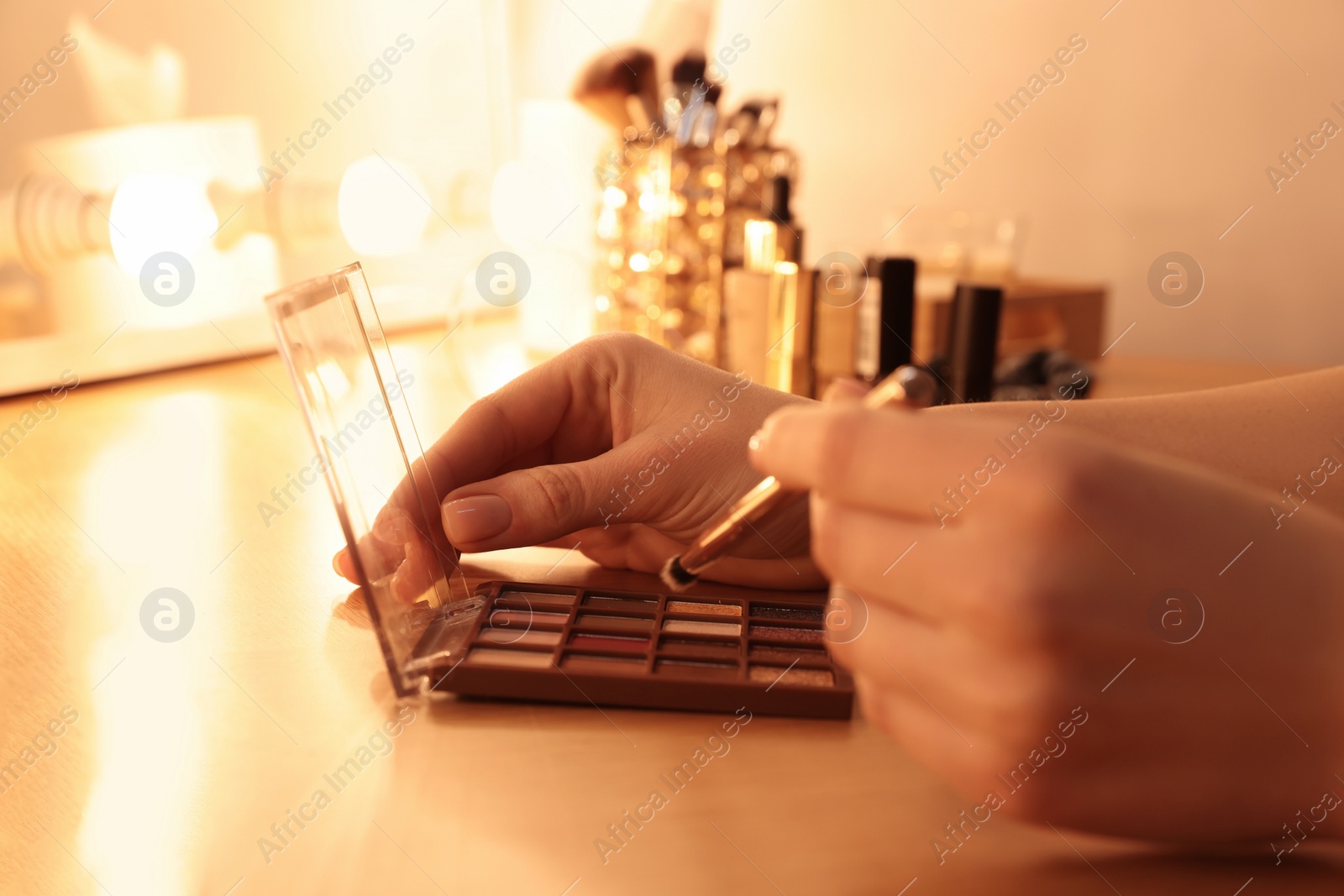 Photo of Woman with eyeshadow palette and brush at dressing table, closeup