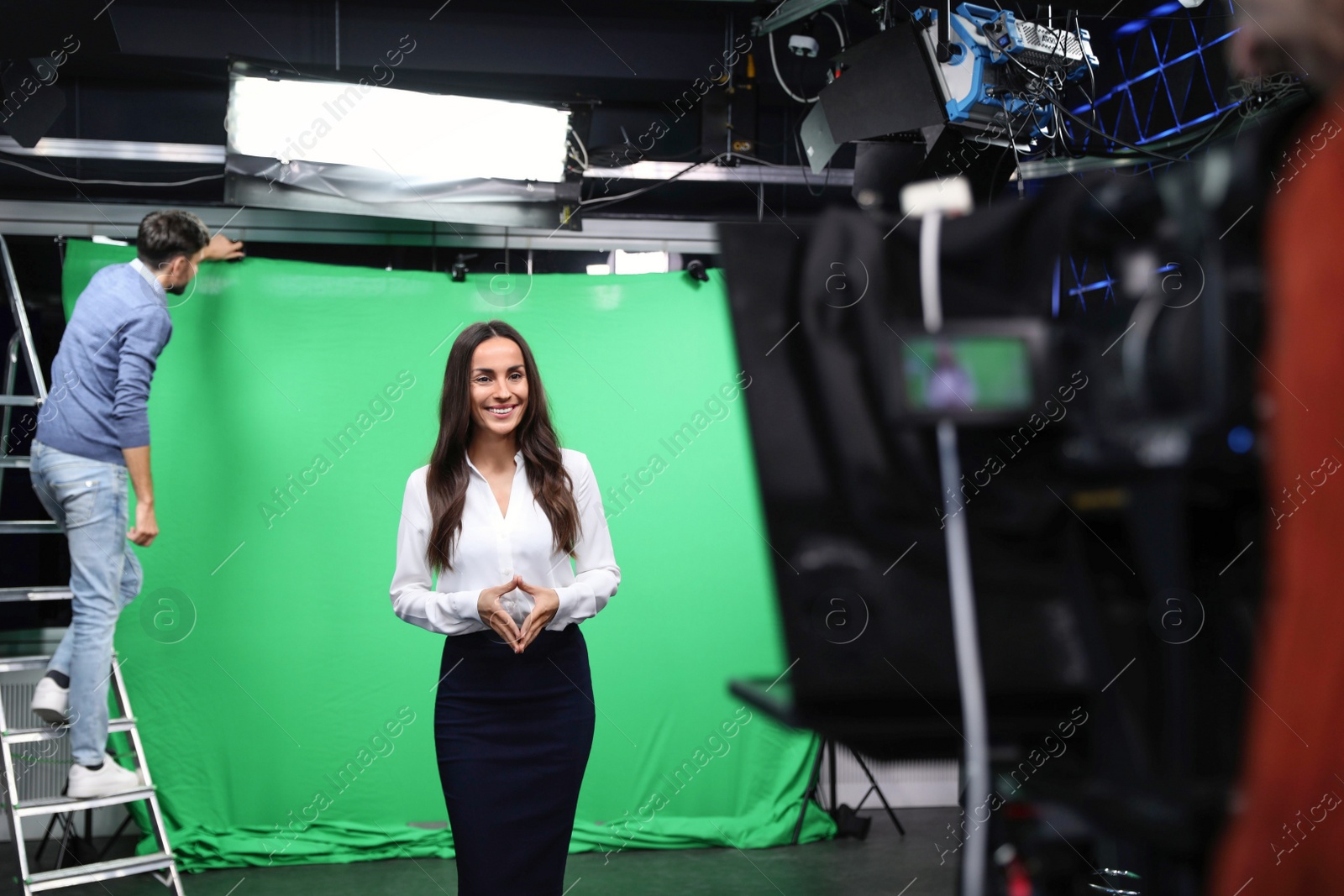 Photo of Presenter, technician and video camera operator working in studio. News broadcasting