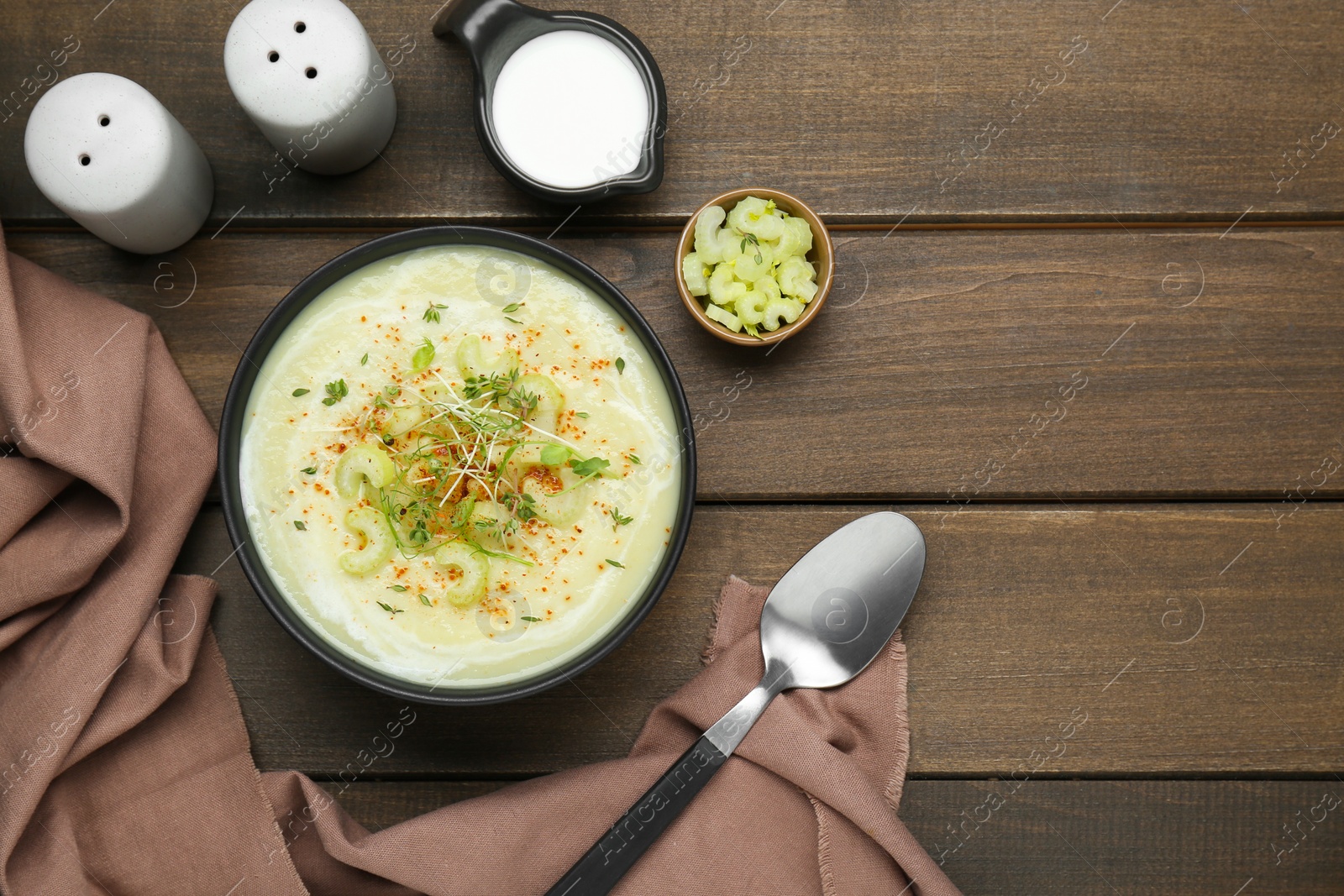 Photo of Bowl of delicious celery soup served on wooden table, flat lay. Space for text