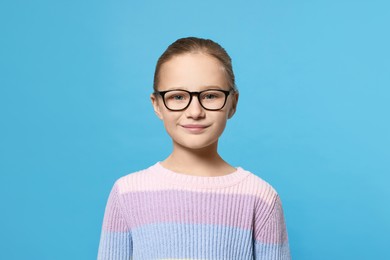 Portrait of cute girl in glasses on light blue background