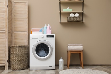 Photo of Modern washing machine near color wall in laundry room interior, space for text