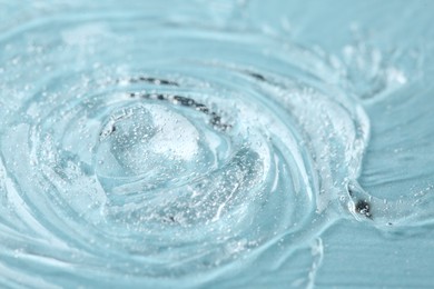 Photo of Clear cosmetic serum on light blue background, macro view