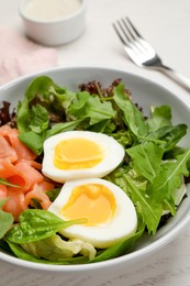 Photo of Delicious salad with boiled egg, salmon and arugula on white table, closeup