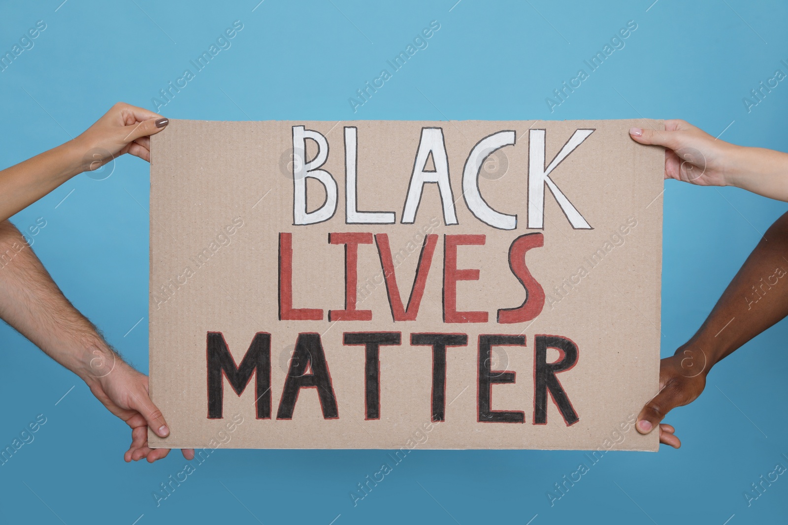 Photo of People holding sign with phrase Black Lives Matter on light blue background, closeup. Racism concept