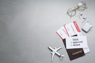 Photo of Flat lay composition with passport, toy plane and glasses on grey background, space for text. Visa receiving