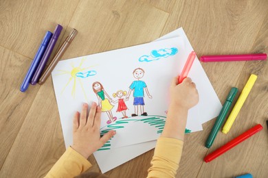 Photo of Little girl drawing with marker on floor, top view. Child`s art