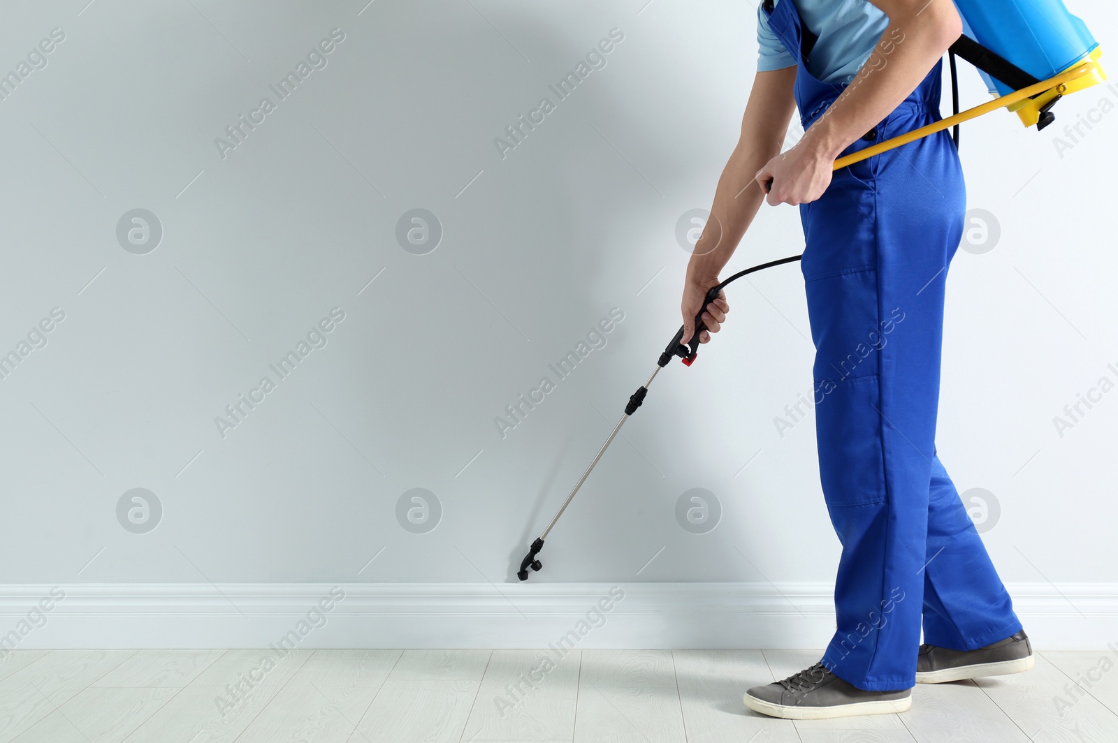 Photo of Pest control worker spraying pesticide in room, closeup. Space for text