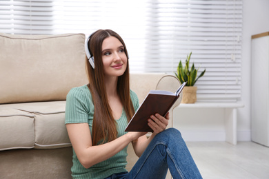 Photo of Woman listening to audiobook near sofa at home