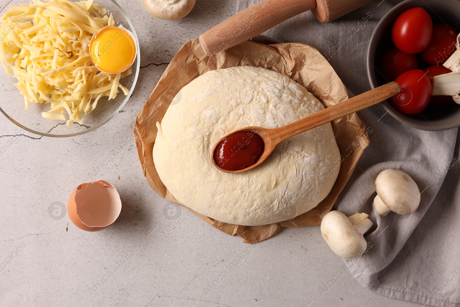 Photo of Pizza dough, products and rolling pin on gray textured table, flat lay