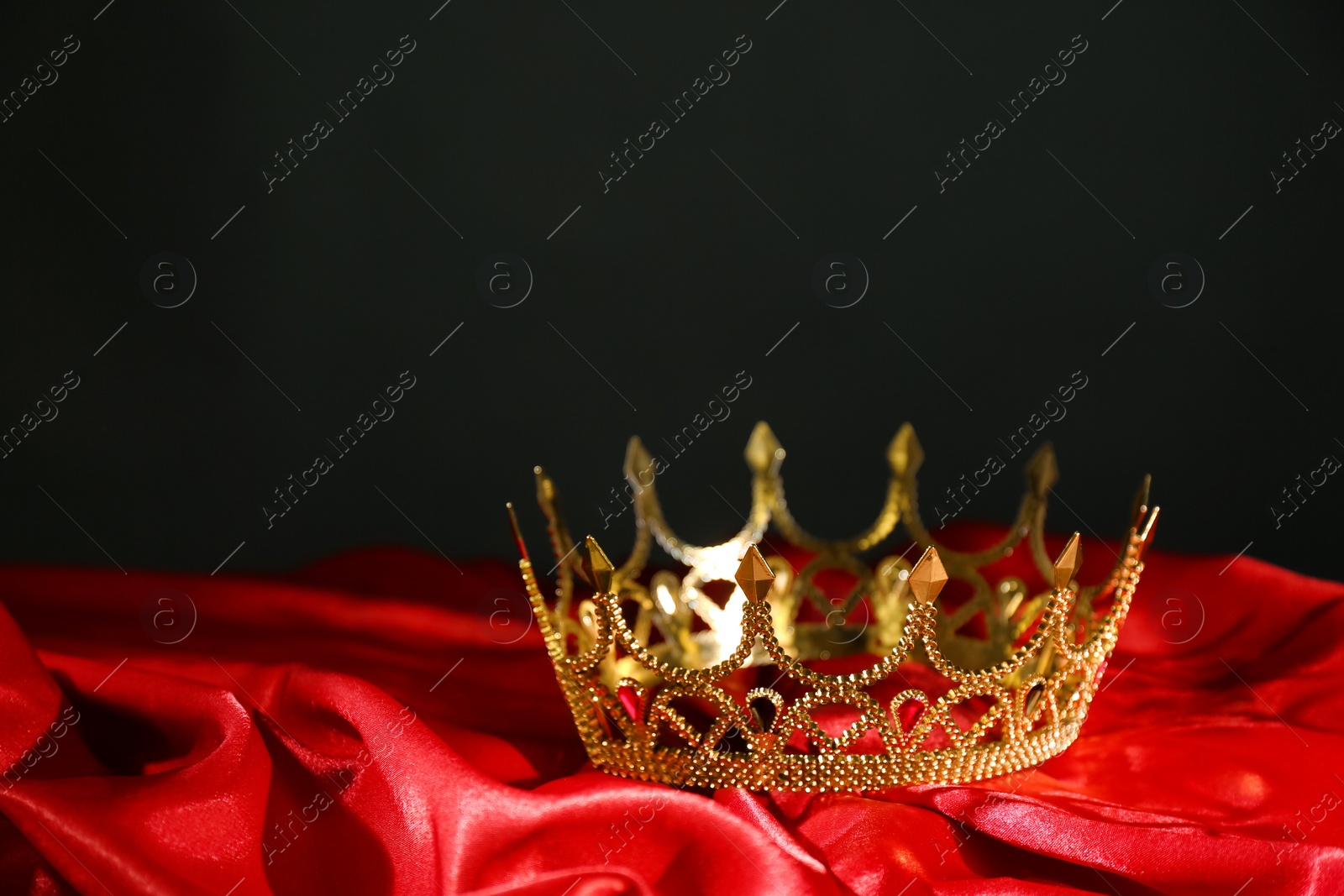 Photo of Beautiful golden crown on red fabric. Fantasy item