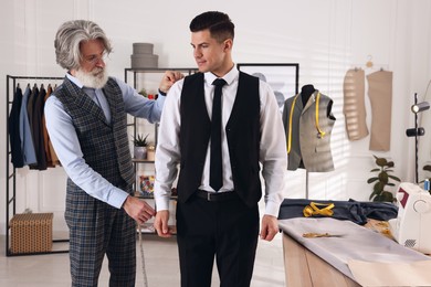 Photo of Professional tailor working with client in atelier