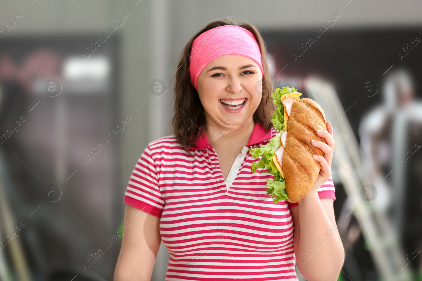 Photo of Overweight woman eating sandwich in gym