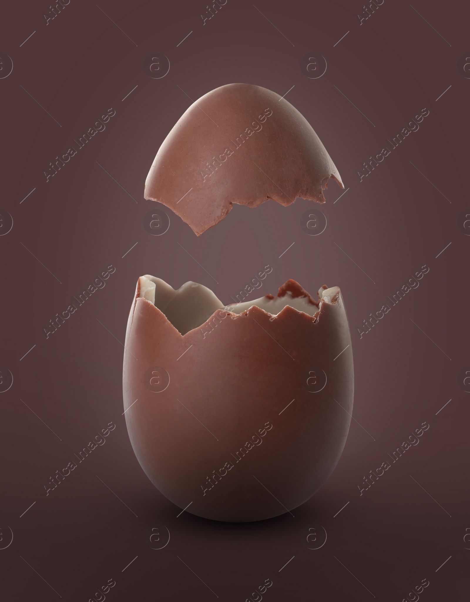 Image of Broken milk chocolate egg on brown background