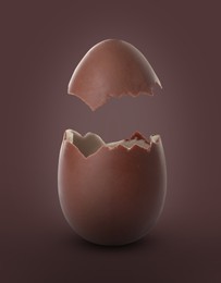 Image of Broken milk chocolate egg on brown background