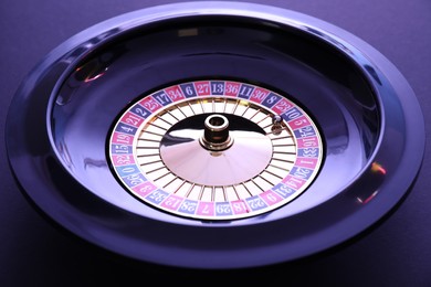 Roulette wheel with ball on dark violet background, closeup. Casino game