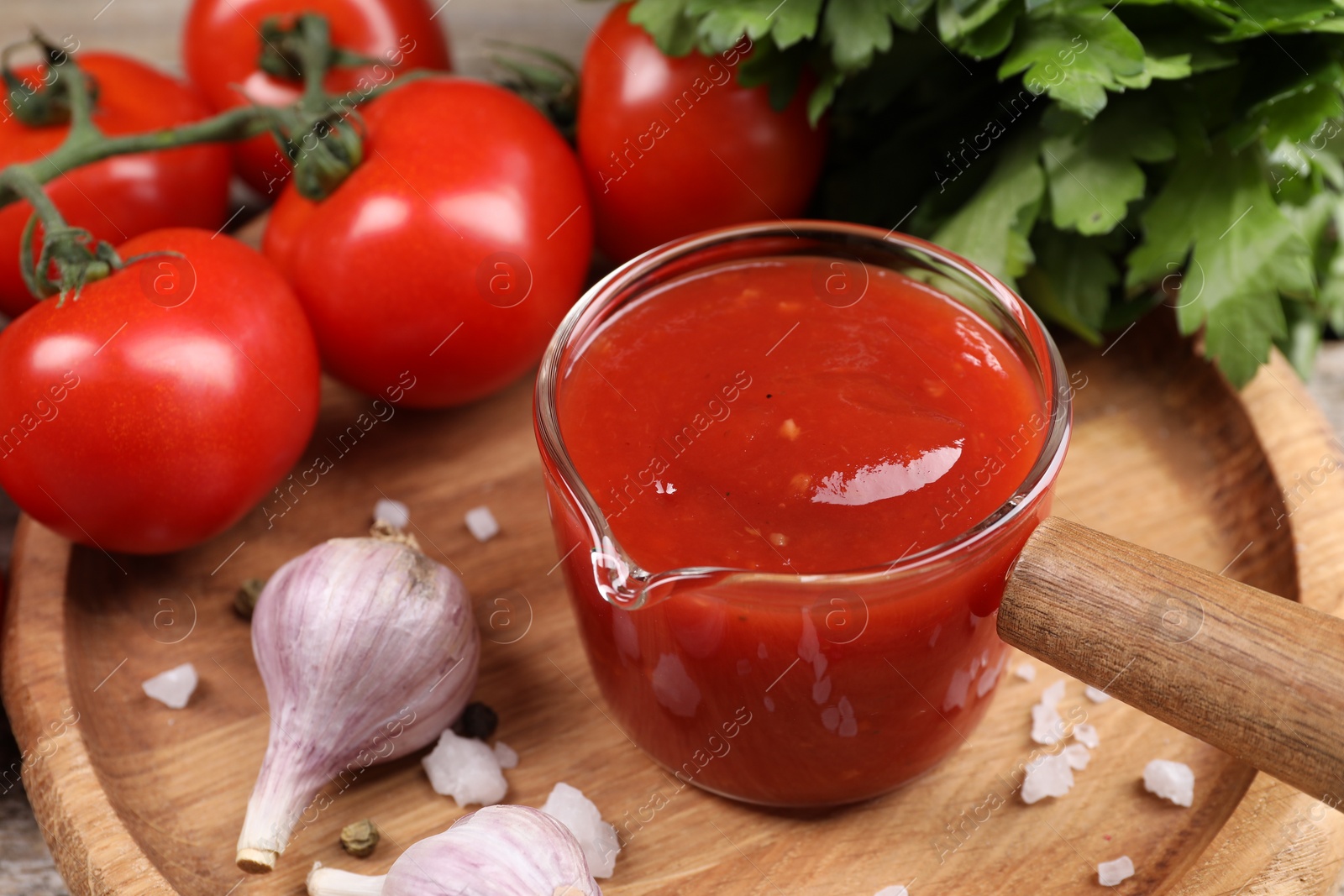 Photo of Delicious ketchup, salt and garlic on table, closeup. Tomato sauce