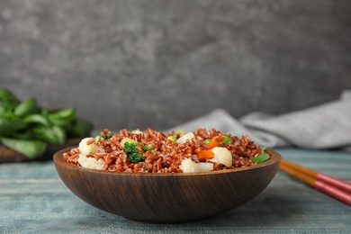 Photo of Plate of brown rice with vegetables on table