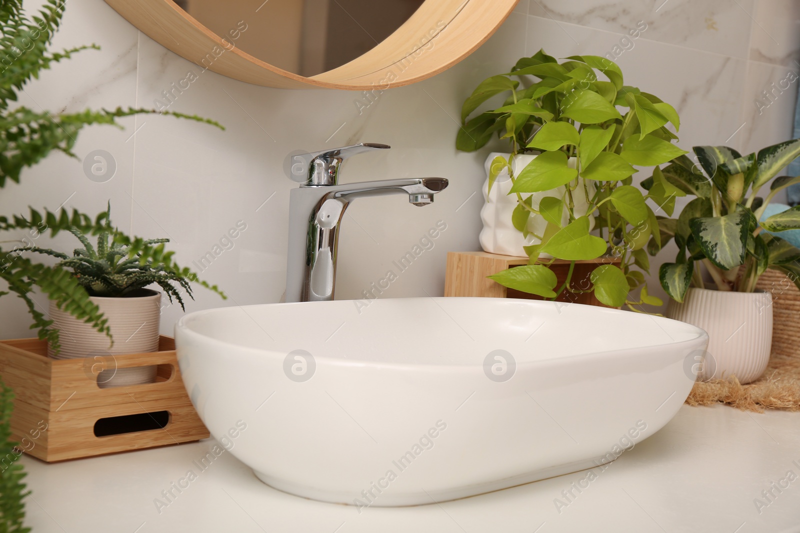 Photo of Bathroom counter with sink and beautiful green houseplants near white marble wall