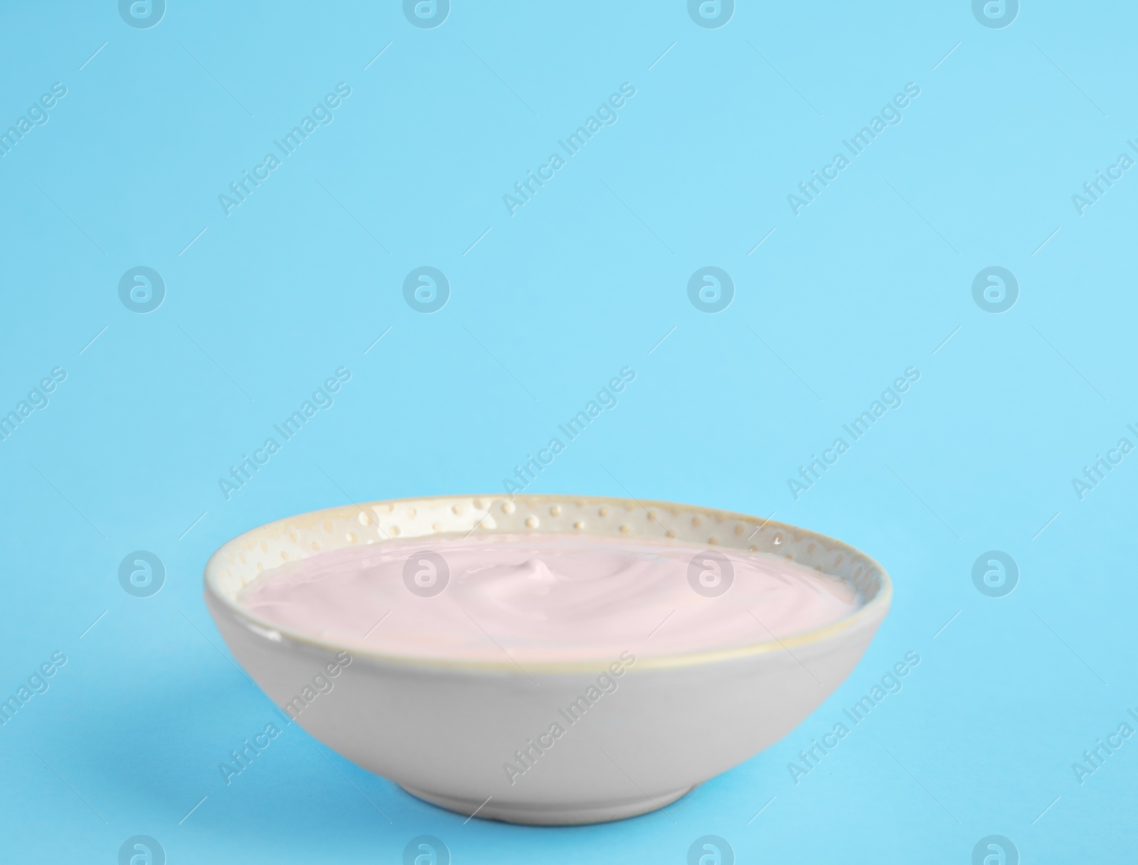 Photo of Tasty organic yogurt on light blue background. Space for text