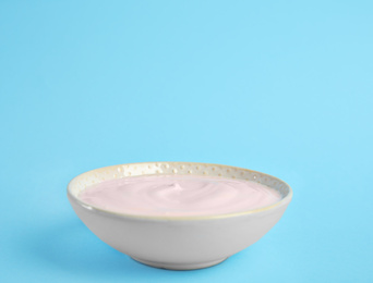 Photo of Tasty organic yogurt on light blue background. Space for text