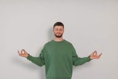Photo of Young man meditating on white background. Zen concept