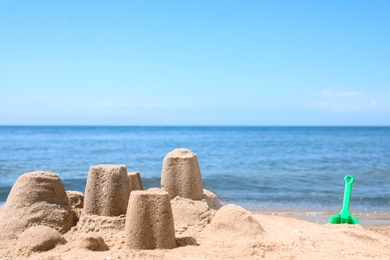 Photo of Little sand figures on beach near sea. Space for text