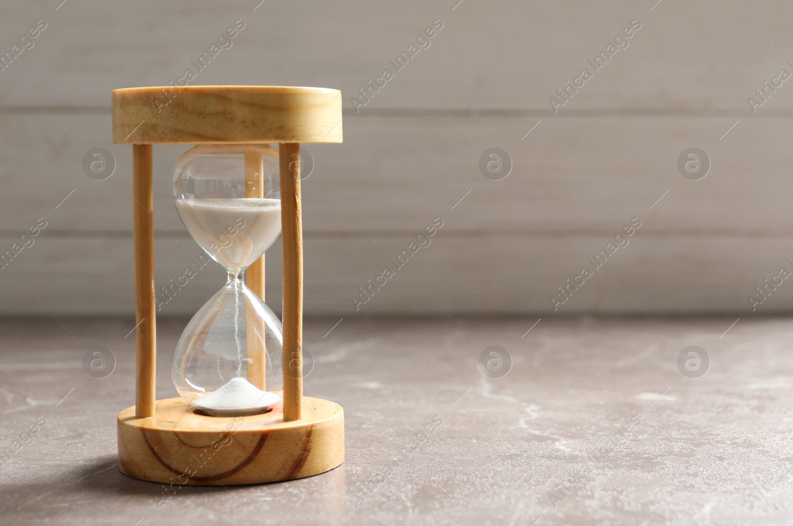 Photo of Hourglass with flowing sand on table. Time management