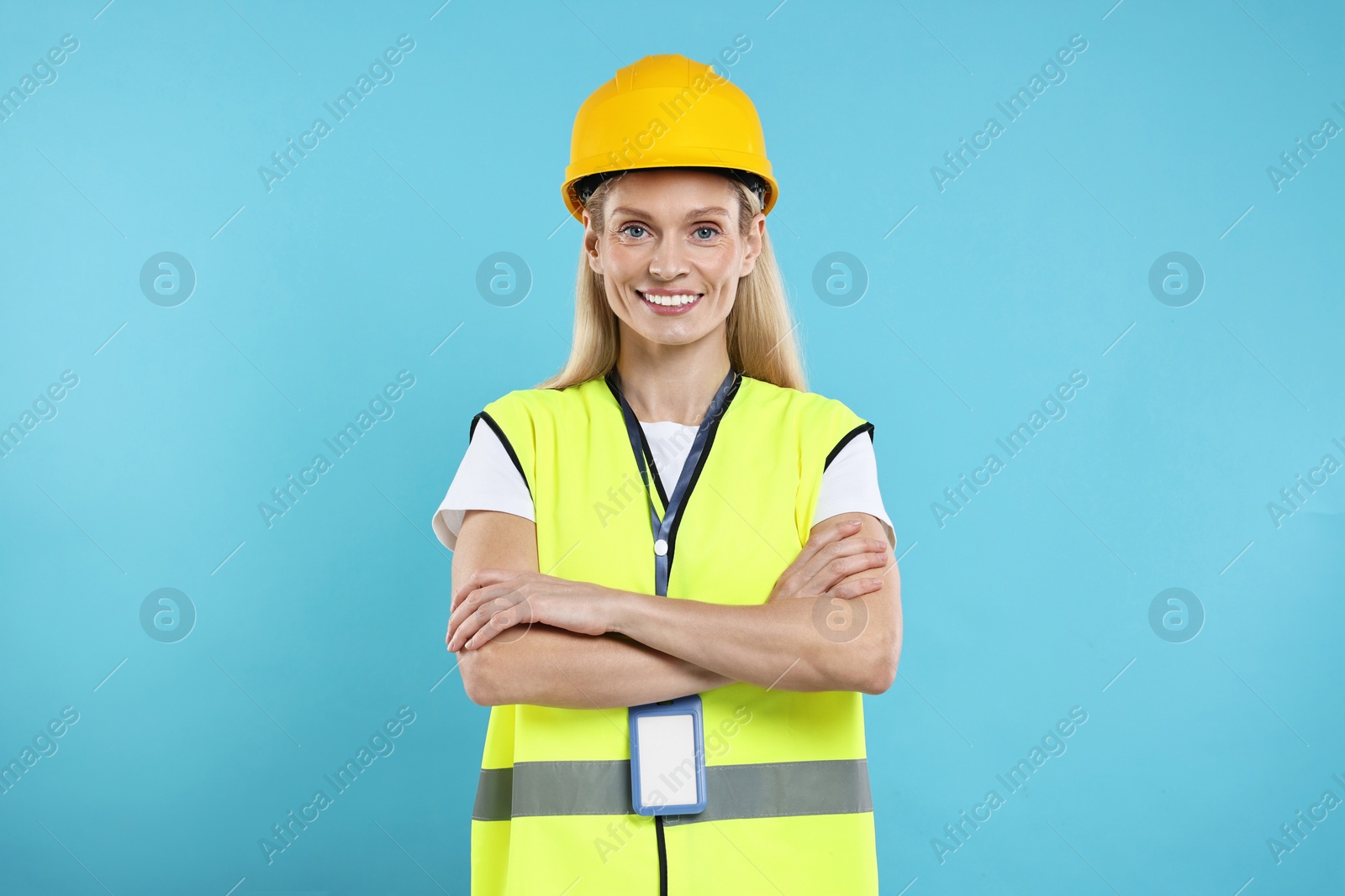 Photo of Engineer with hard hat and badge on light blue background
