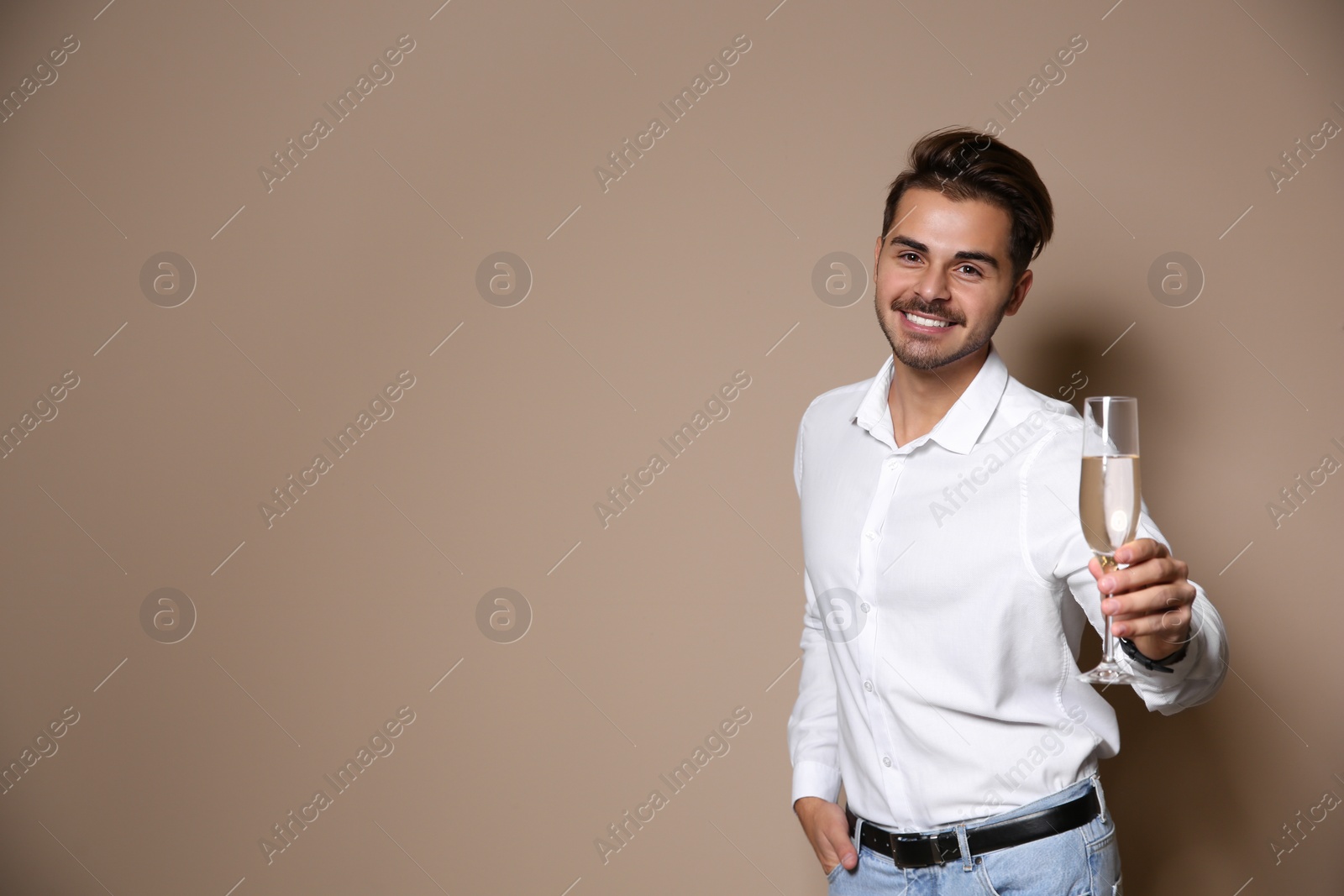 Photo of Handsome man with glass of champagne on color background. Space for text