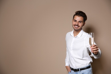 Handsome man with glass of champagne on color background. Space for text