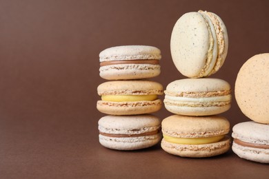 Photo of Pile of delicious colorful macarons on brown background. Space for text