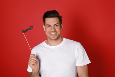 Happy man with fake mustache on red background