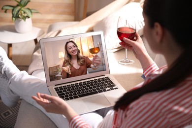 Image of Woman with glass of wine having online party via laptop at home during quarantine lockdown, closeup