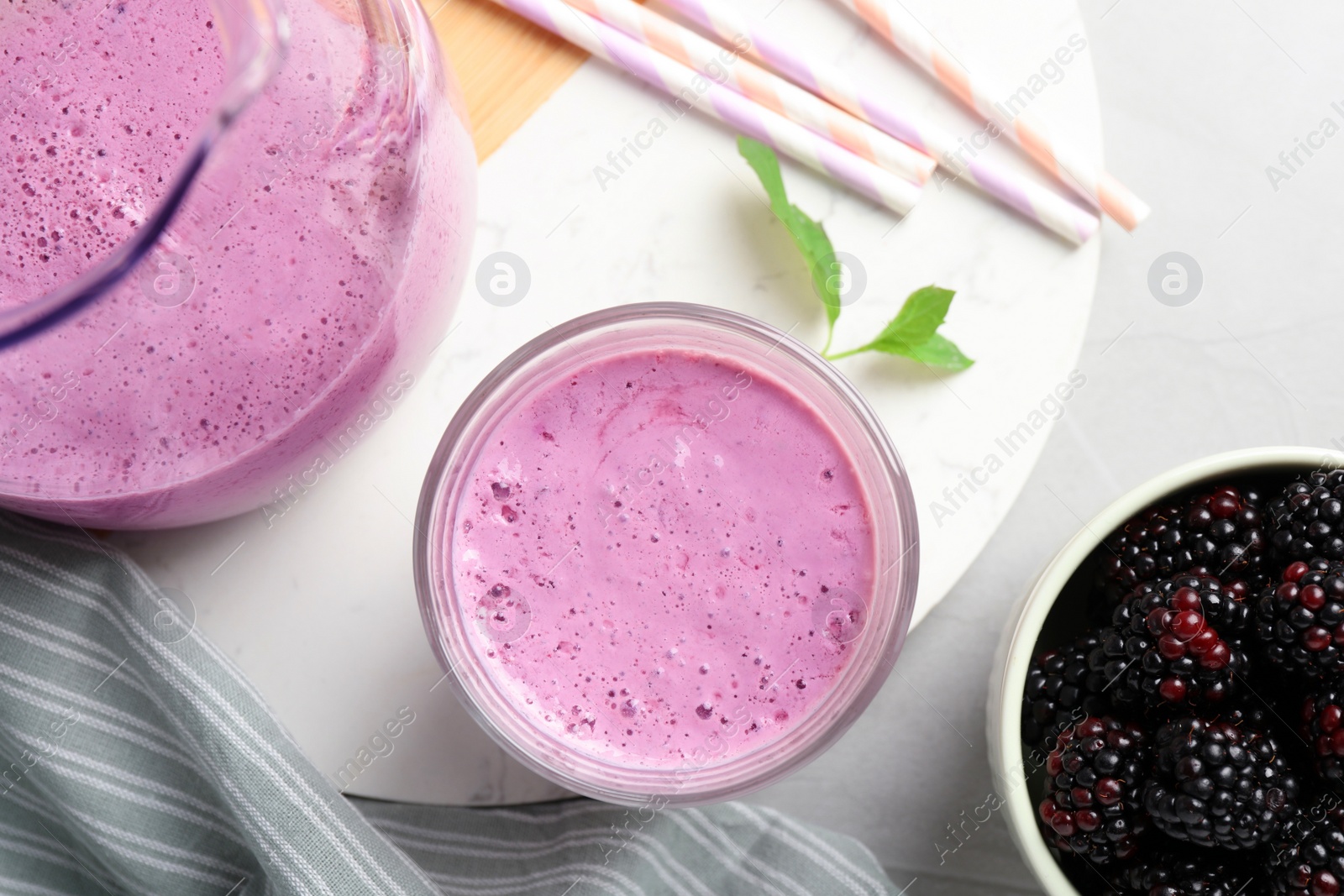 Photo of Delicious blackberry smoothie and berries on white table, flat lay