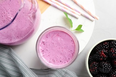 Photo of Delicious blackberry smoothie and berries on white table, flat lay
