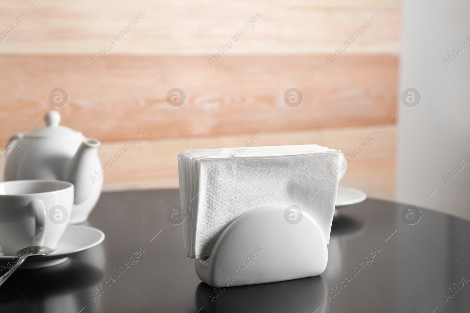 Photo of Ceramic napkin holder with paper tissues on served table. Tea time