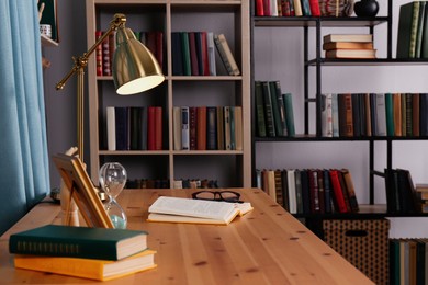 Wooden table and collection of different books on shelves in home library