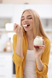 Young woman with yogurt on blurred background