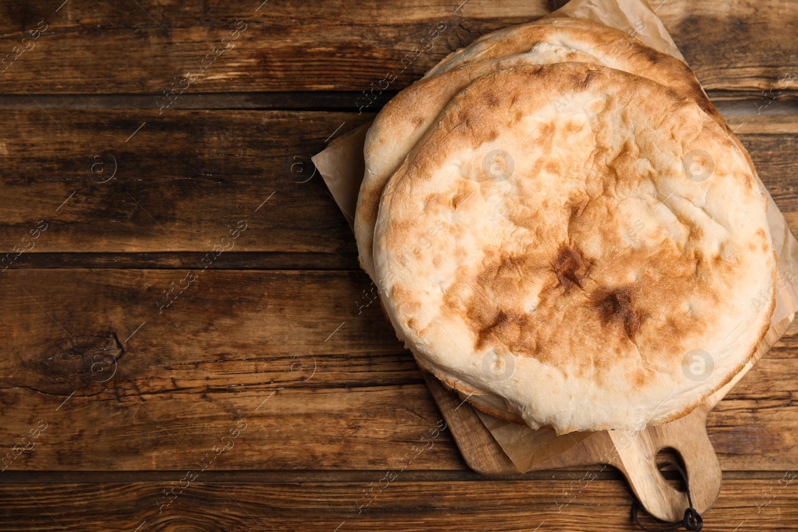 Photo of Loaves of delicious homemade pita bread on wooden table, top view. Space for text