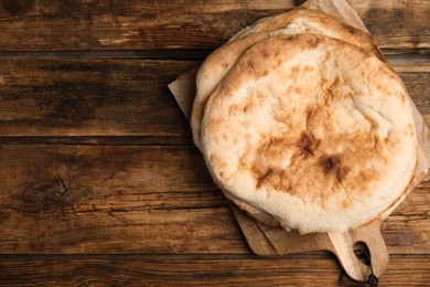 Photo of Loaves of delicious homemade pita bread on wooden table, top view. Space for text