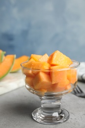 Cubes of tasty ripe cantaloupe melon in glass bowl on grey table